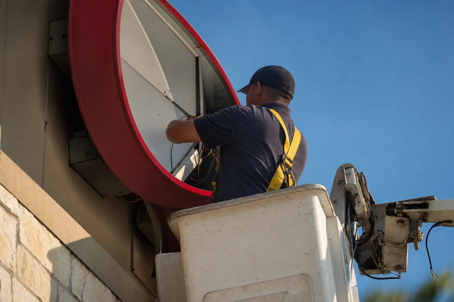 Sign electrician servicing a commercial storefront sign from a bucket lift in Texas